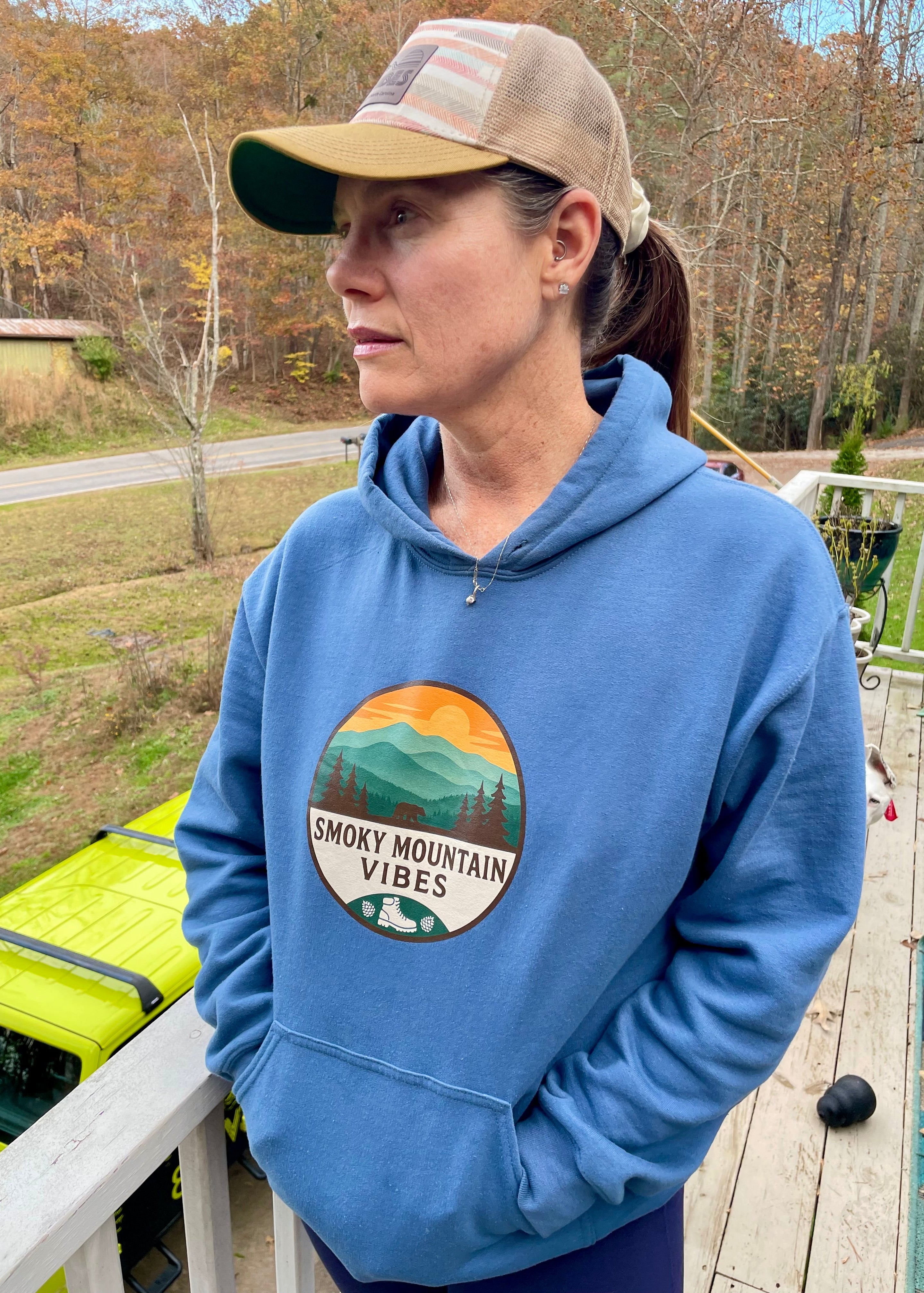 Person wearing a blue hoodie with 'Smoky Mountain Vibes' design outdoors.