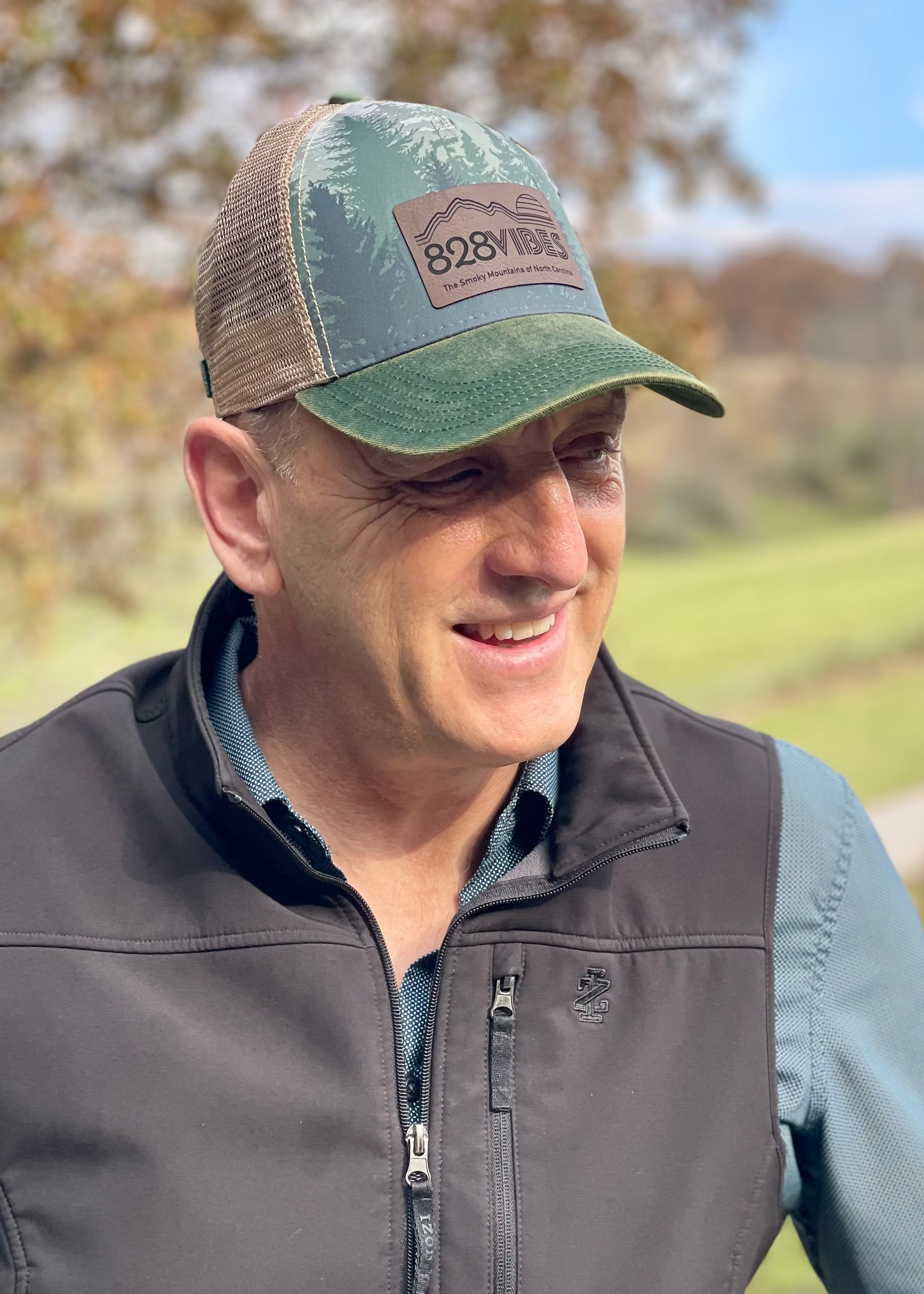 Man wearing a cap with a logo and vest outdoors
