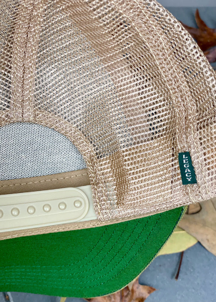 Close-up of a green and beige mesh cap with a visible brand tag.