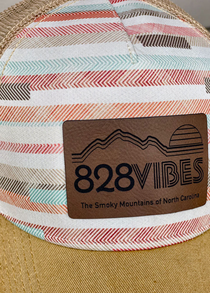 Striped cap with a wooden '828 Vibes' badge on a blurred background