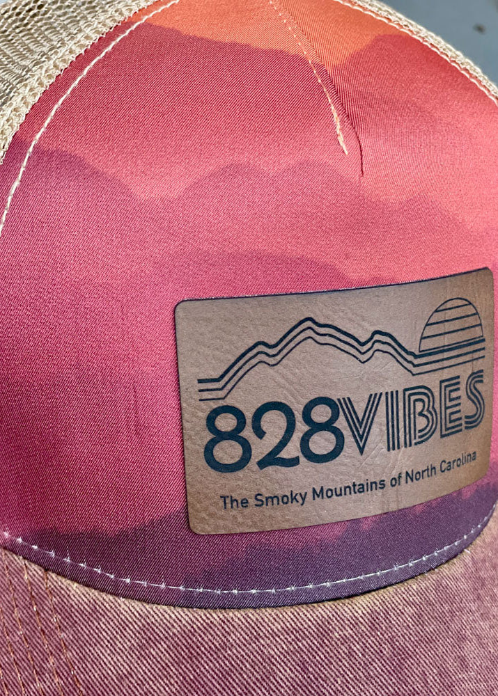 Pink and purple cap with '828 Vibes' logo and text on a blurred background