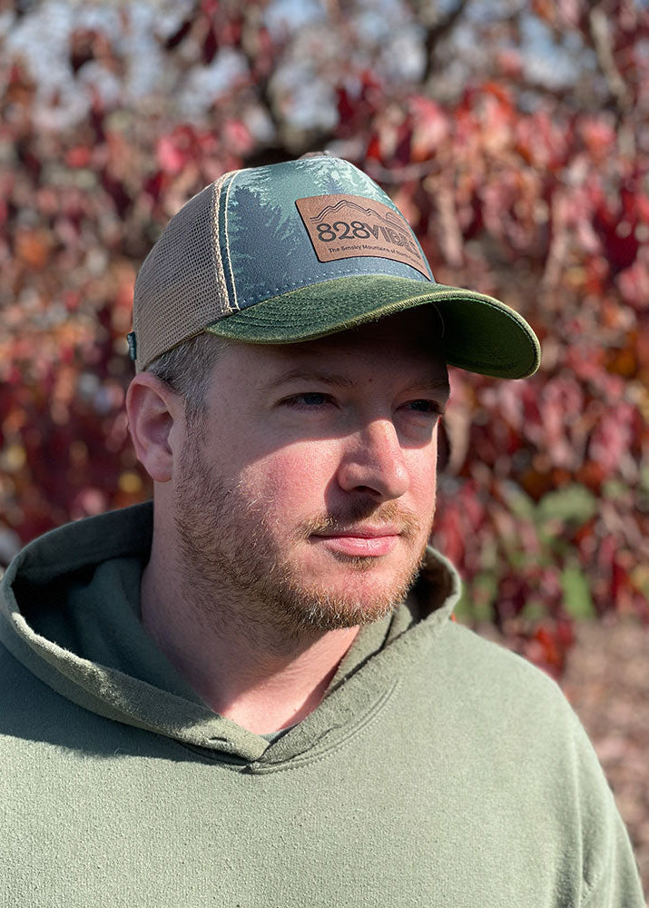 Man wearing a green cap with a logo in front of a blurred natural background