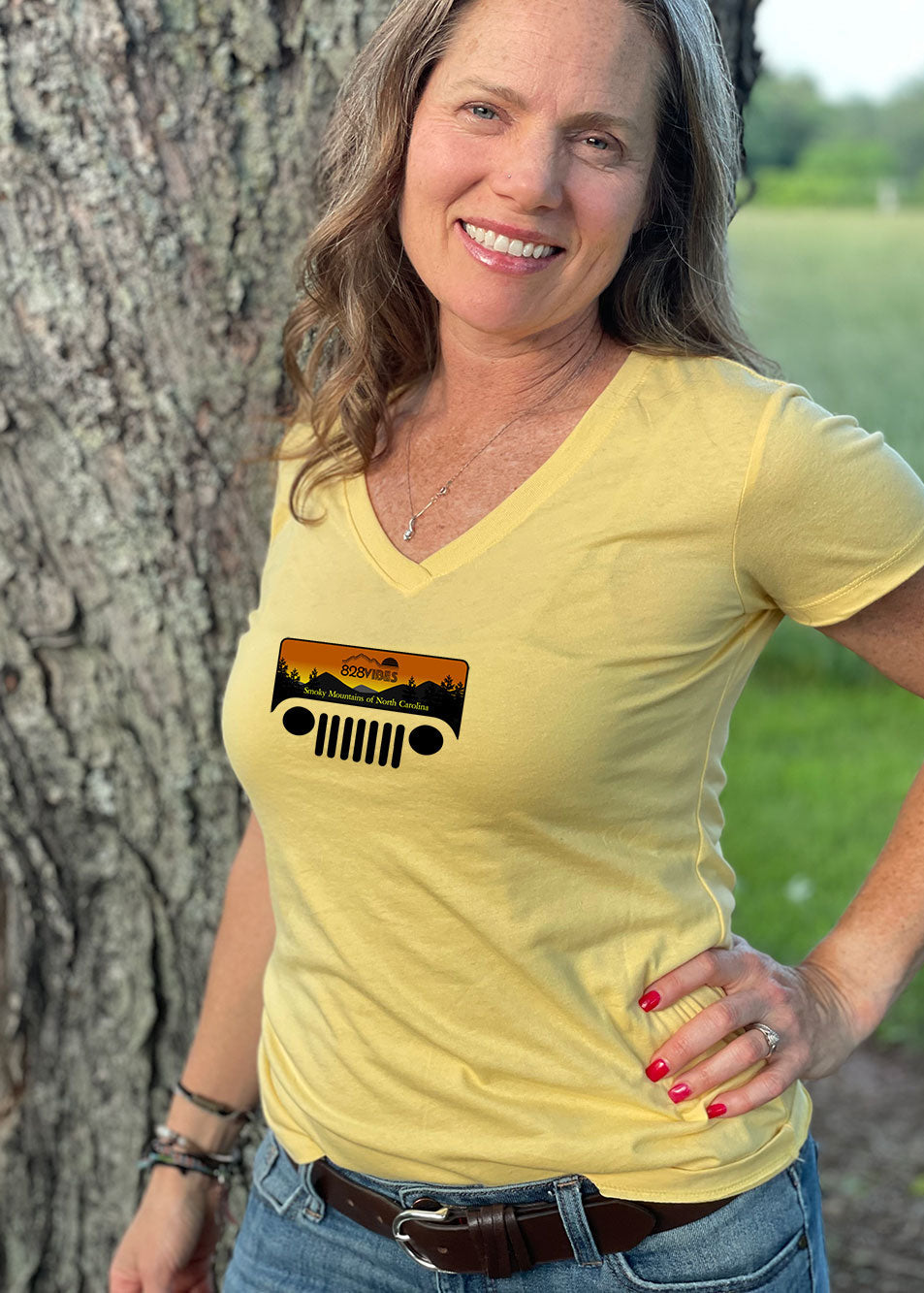 A woman wearing a yellow V-neck T-shirt with a graphic of a Jeep in the Smokies on the front.