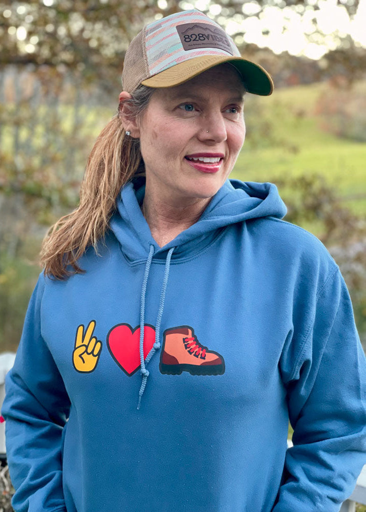 Person wearing a blue hoodie with symbols and a cap outdoors