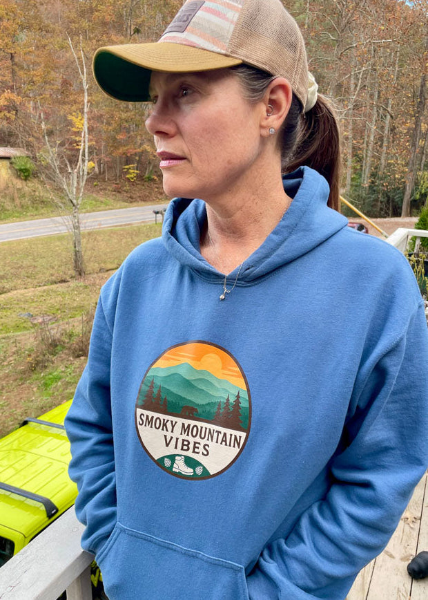 Person wearing a blue hoodie with 'Smoky Mountain Vibes' graphic, standing outdoors.