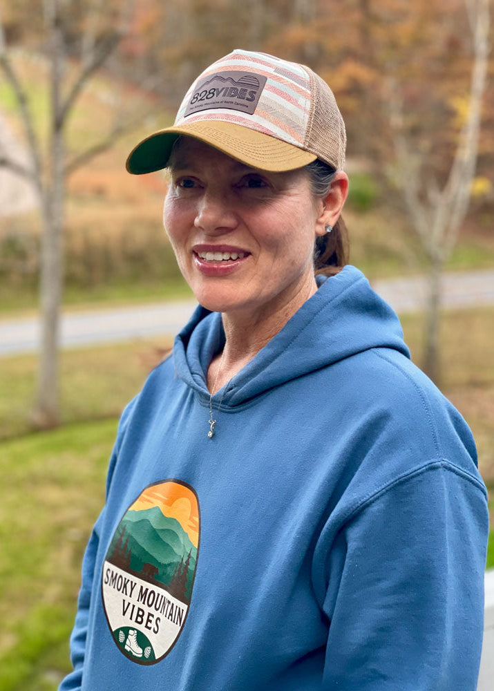 Person wearing a blue hoodie with 'Smoky Mountain Vibes' logo and a cap outdoors.