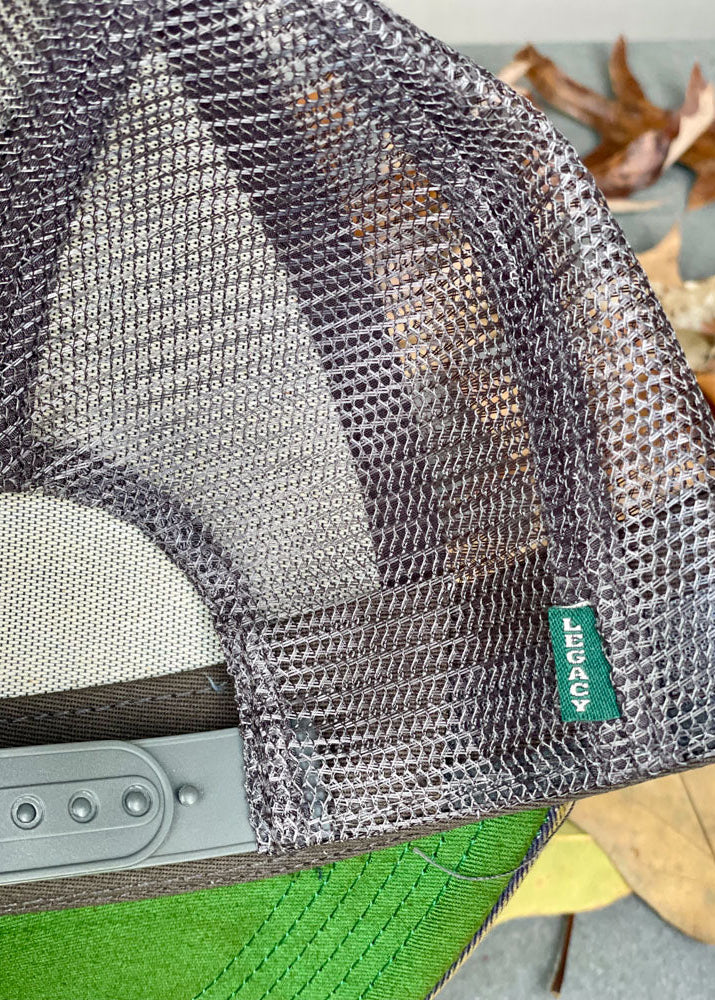 Close-up of a mesh bag with a brand label on a green surface with leaves.
