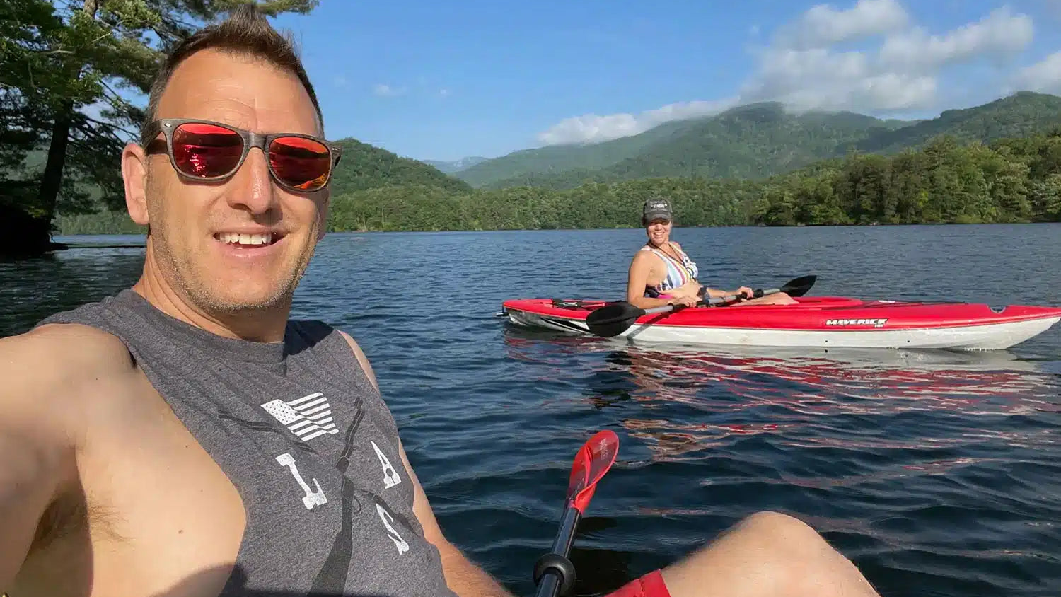 Two people kayaking on a lake with mountains in the background